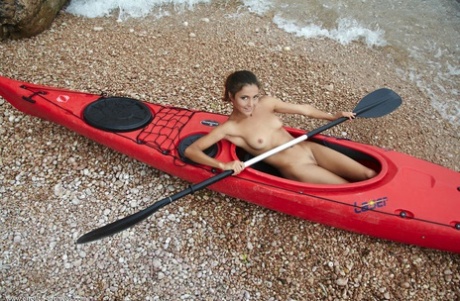 Butt naked babe Sati poses in the kayak on the wild beach