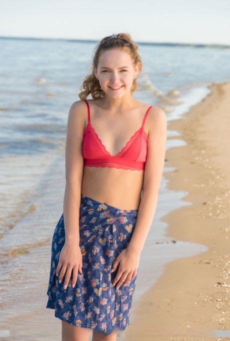 Adorable teen Faina Bona gets naked on the beach before oiling her cute pussy