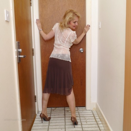 Mature blonde Llaria exposes her stocking tops with her legs crossed in heels