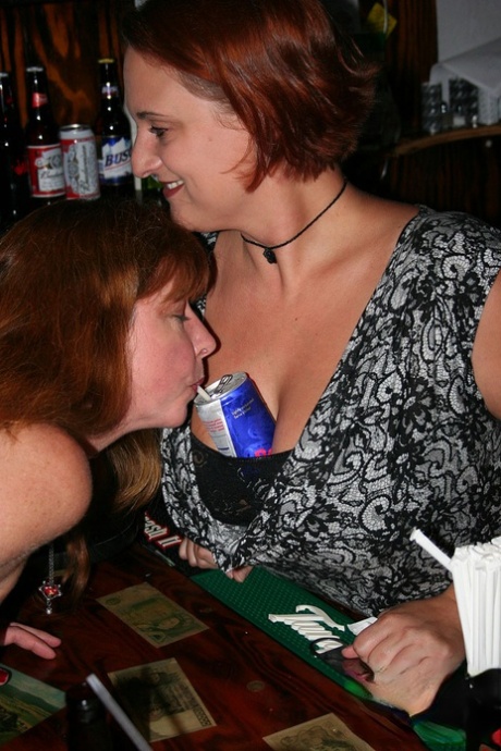 Playful amateur mature swinger wives teasing and French kissing at a party