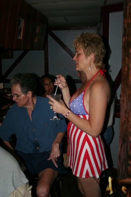 Playful amateur mature swinger wives teasing and French kissing at a party