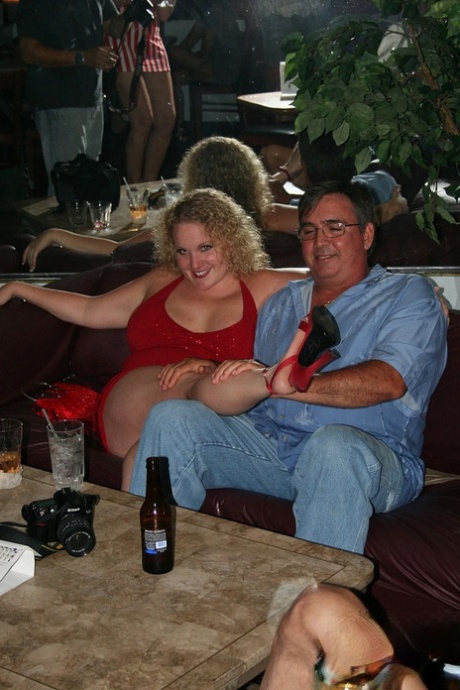 Playful amateur mature swinger wives teasing and French kissing at a party