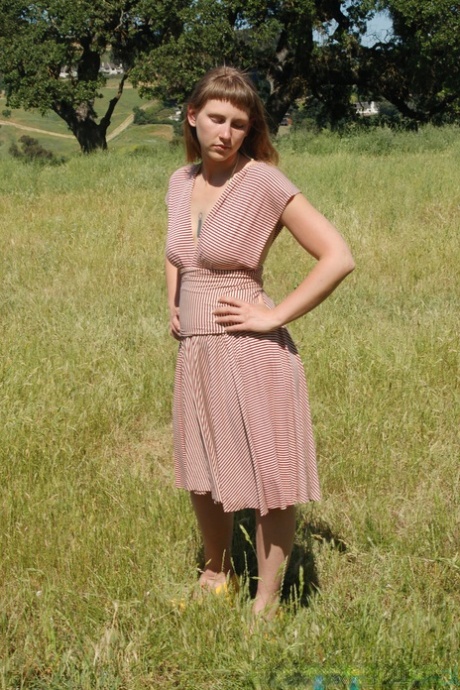 Short amateur teen Miel undresses in a field and shows her tits & hairy twat