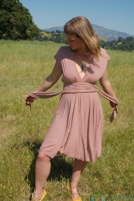 Short amateur teen Miel undresses in a field and shows her tits & hairy twat