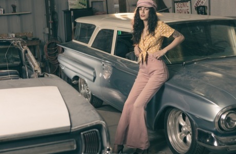 Glamorous brunette model posing in her garage in her hot outfit