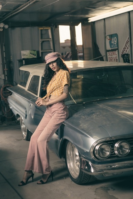 Glamorous brunette model posing in her garage in her hot outfit
