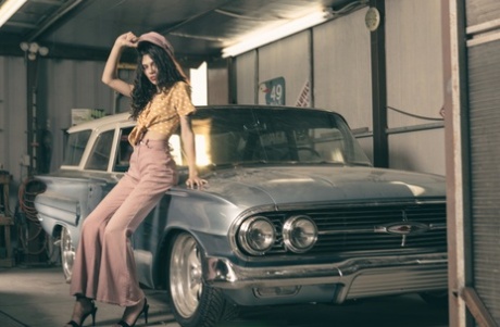 Glamorous brunette model posing in her garage in her hot outfit